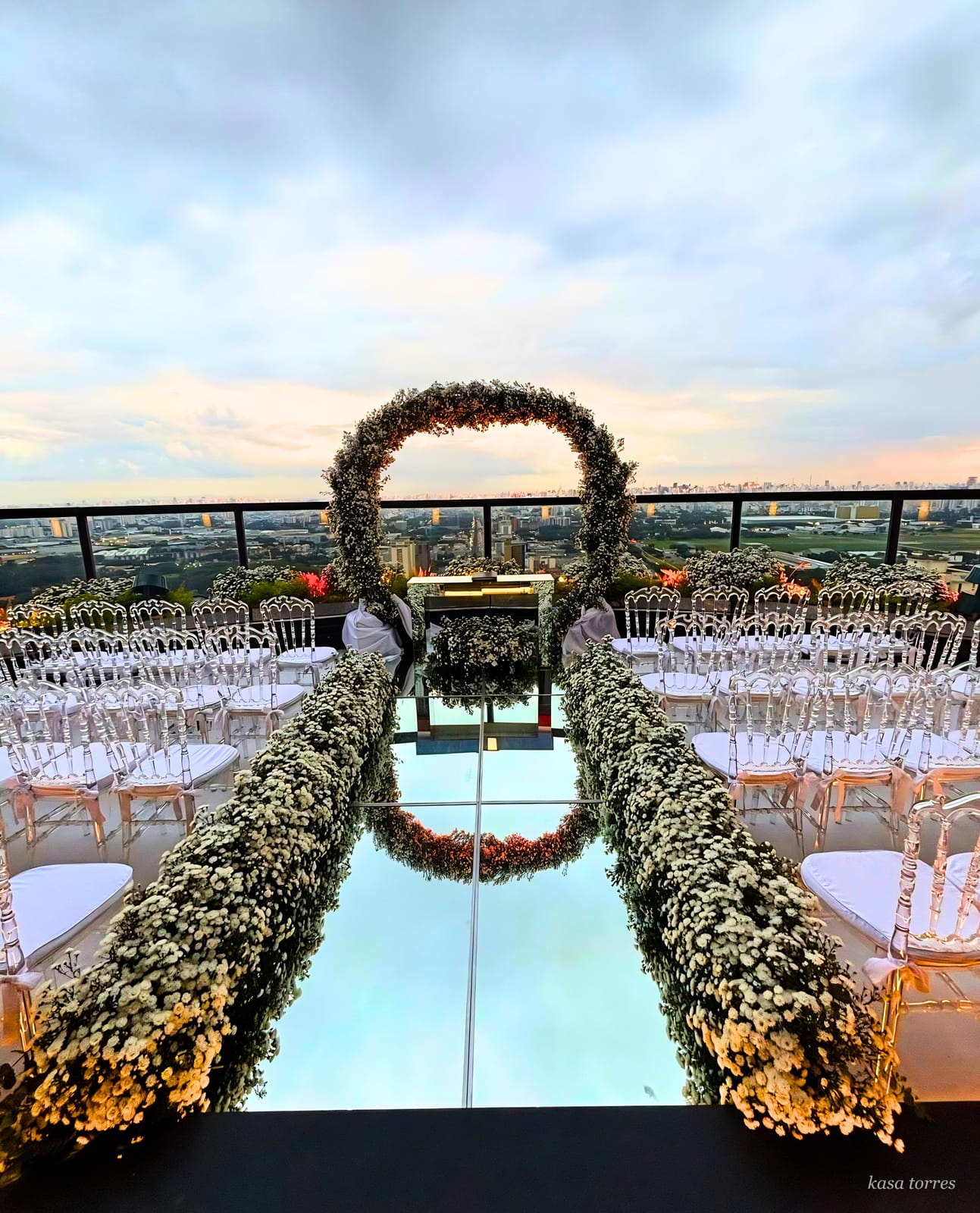 Cerimônia de casamento rooftop com vista da cidade ao entardecer e arco de mosquitinho — Kasa Torres